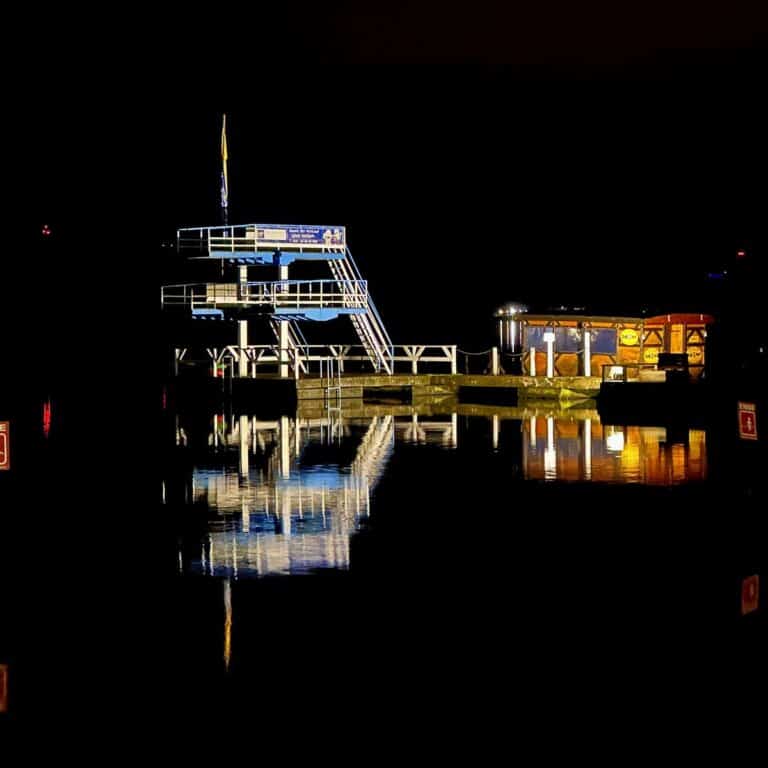 Servus 2023 - Ahoi 2024-Beitragsbild-Seebad Friedrichshagen bei Nacht mit erleuchtetem Sprungturm